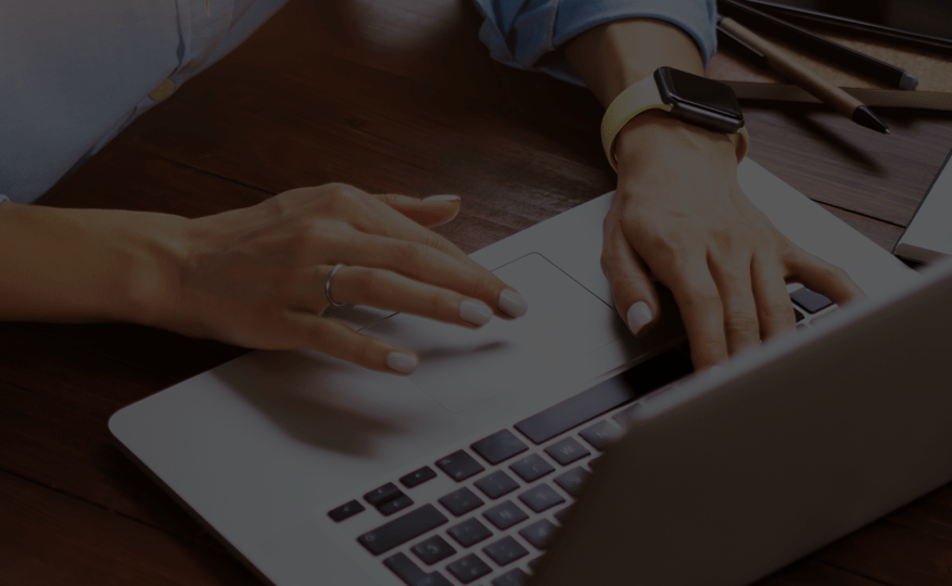 Hands held over a chrome laptop